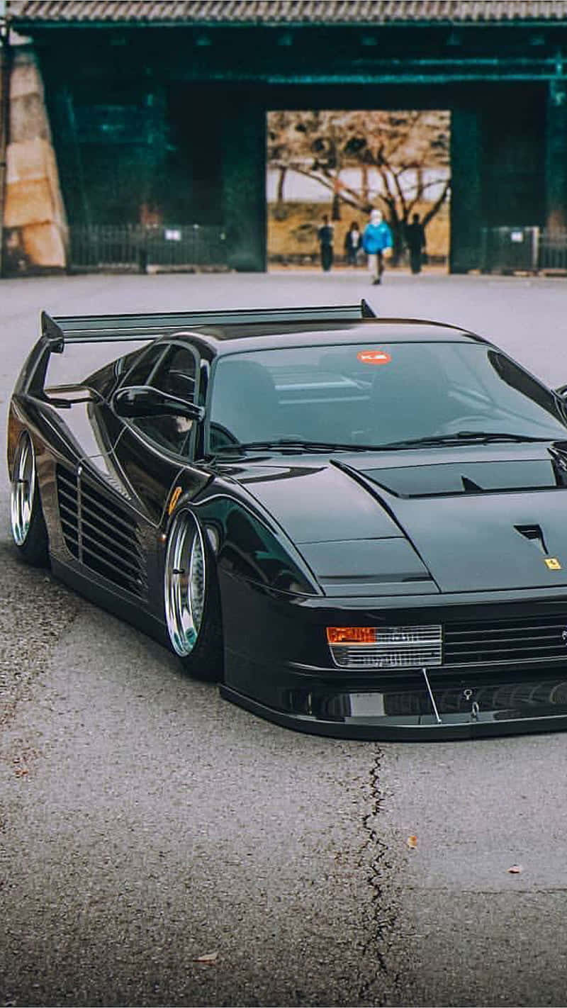 A Black Sports Car Parked In Front Of A Building Wallpaper