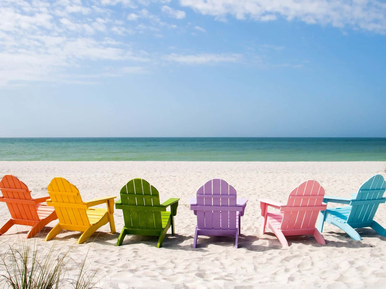 A Colorful Array Of Chairs By The Beach Wallpaper