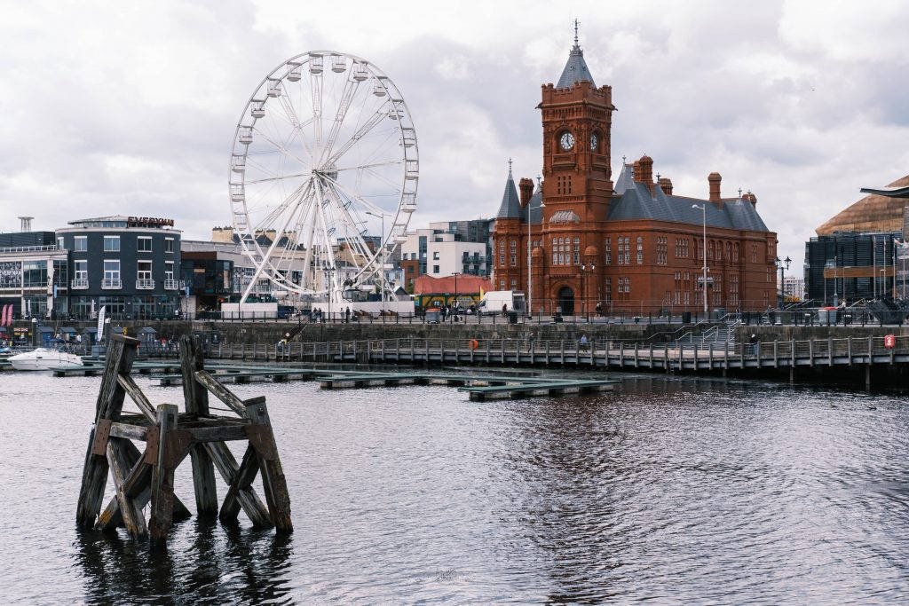 A Ferris Wheel And A Building In The Water Wallpaper