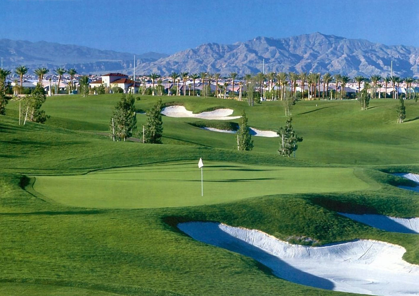 A Golf Course With Mountains In The Background Wallpaper