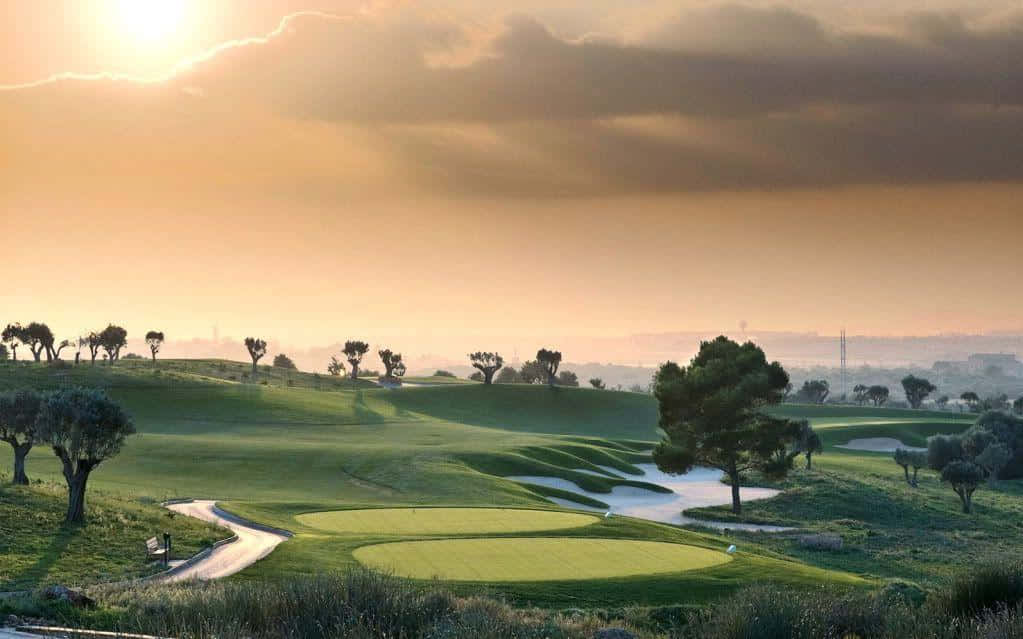 A Golf Course With Trees And A Sunset Wallpaper