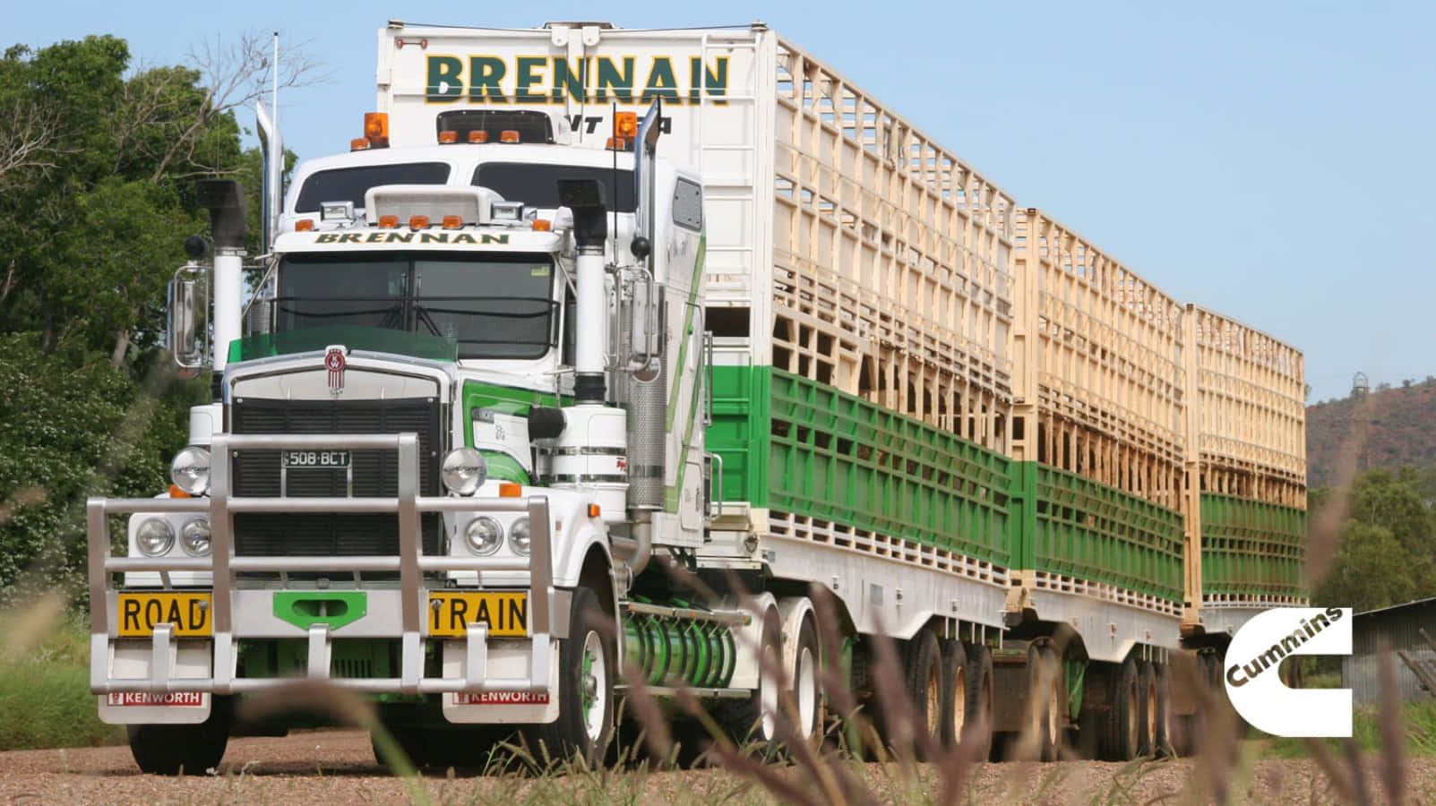 A Green And White Truck Driving Down A Dirt Road Wallpaper