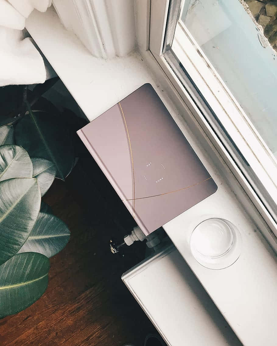 A Laptop On A Window Sill Next To A Plant Wallpaper