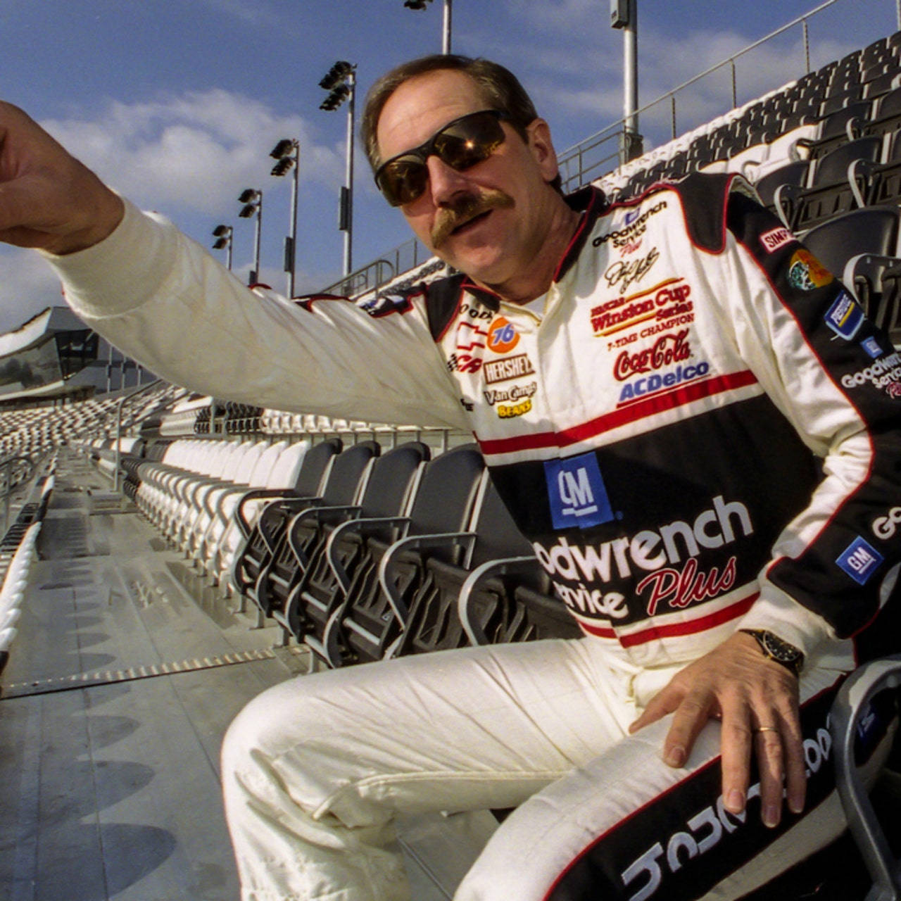 A Man In A Nascar Uniform Is Sitting On A Bench Wallpaper