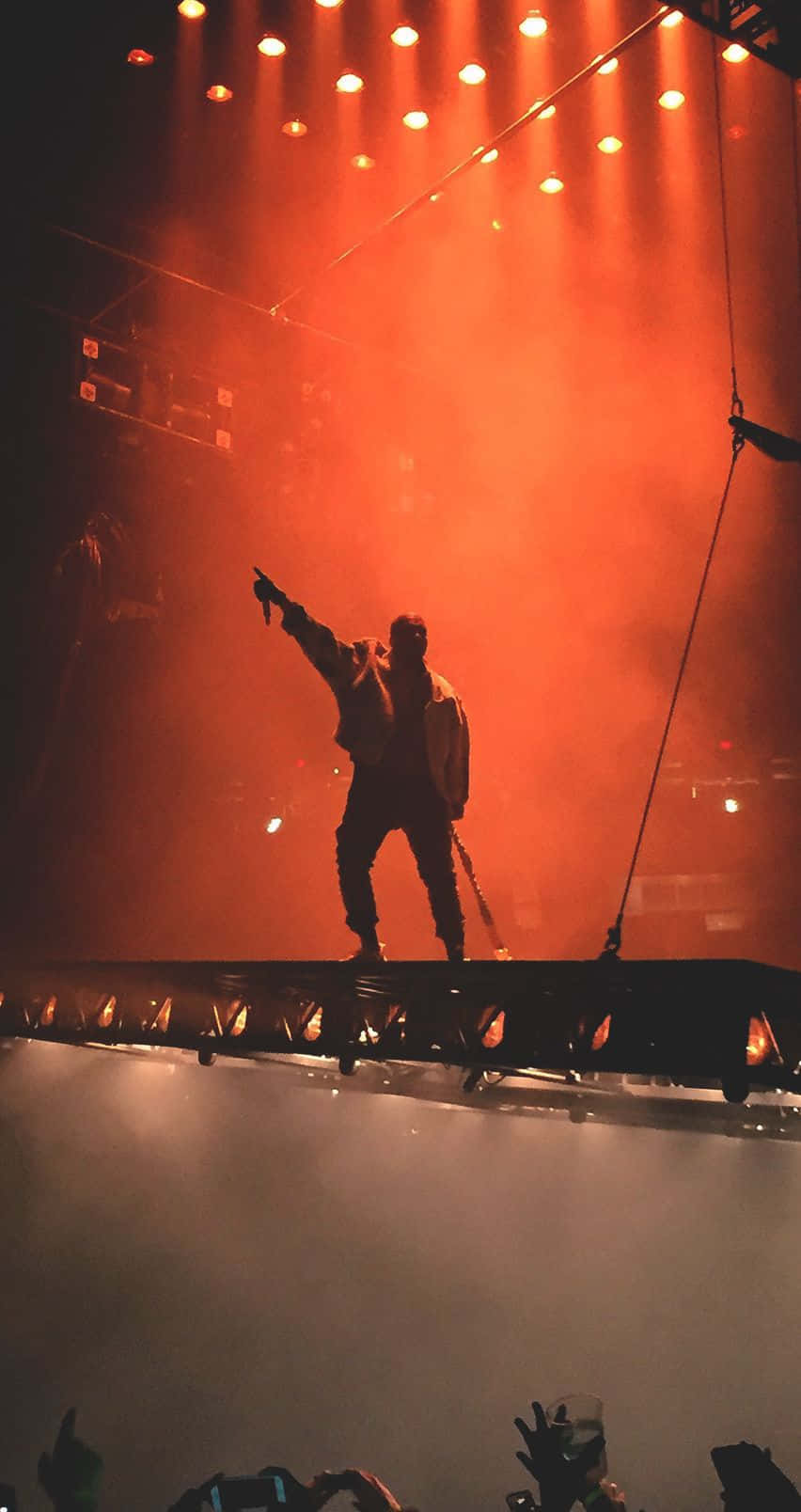 A Man Is Standing On A Stage With A Light On Wallpaper