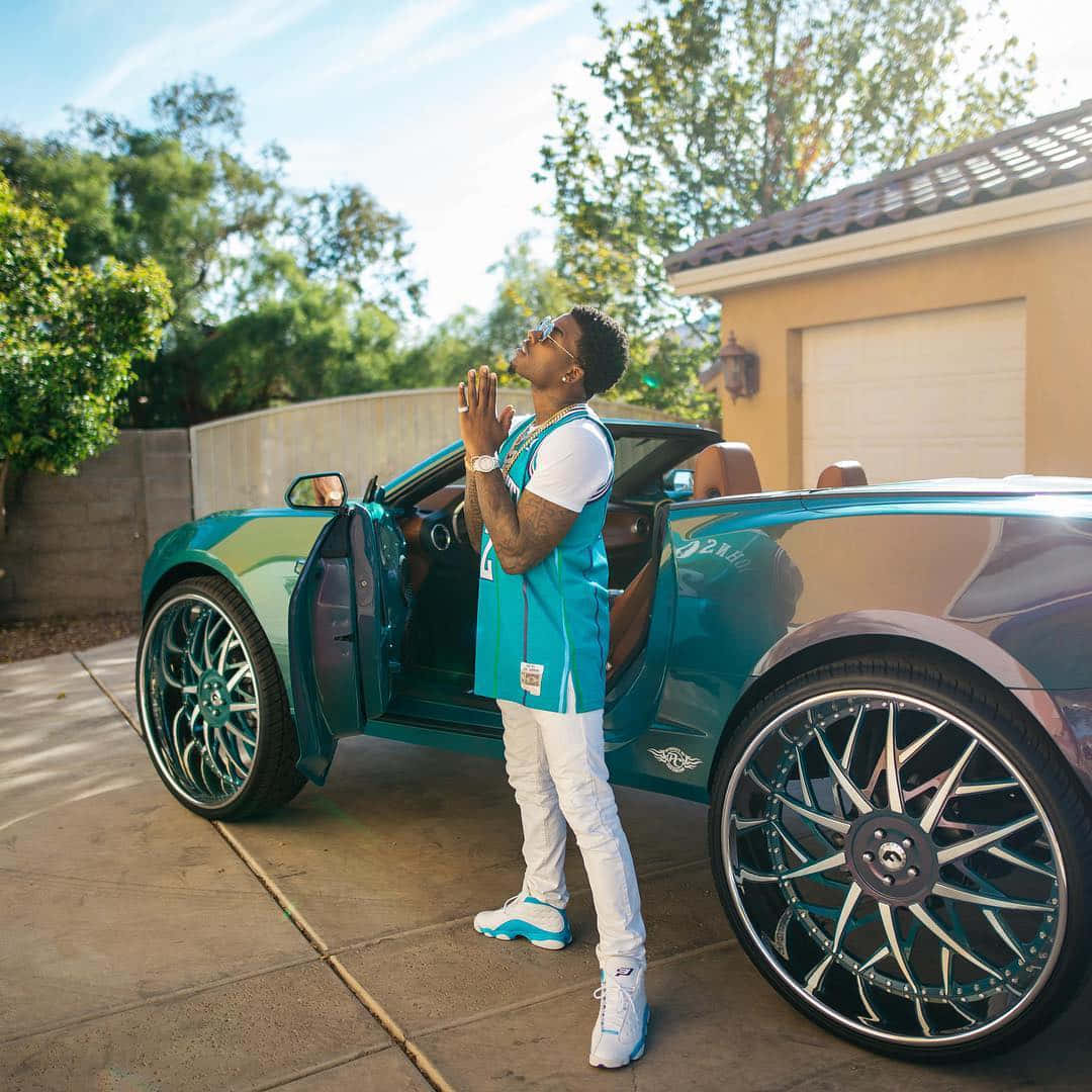 A Man Standing Next To A Blue Bentley Sports Car Wallpaper