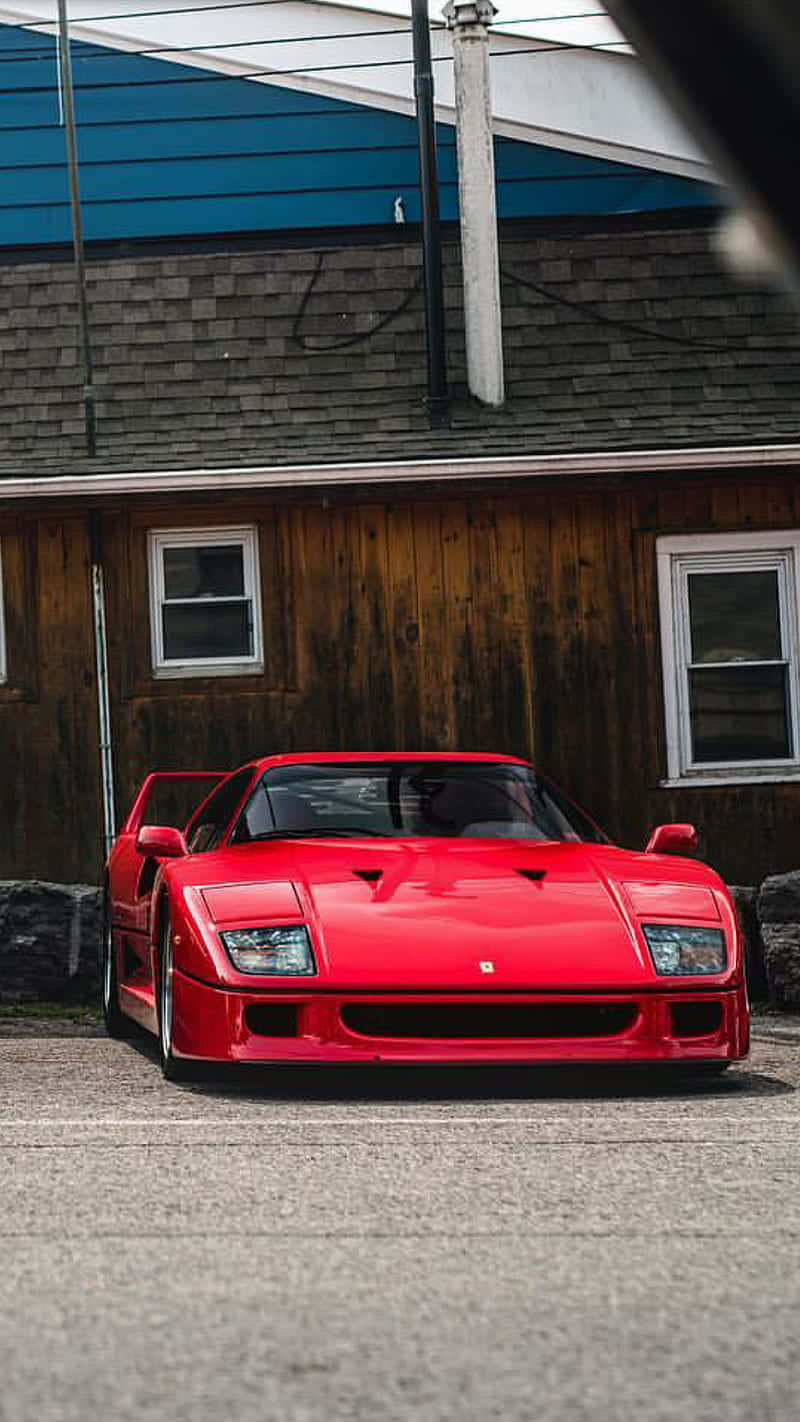 A Red Sports Car Parked In Front Of A Building Wallpaper