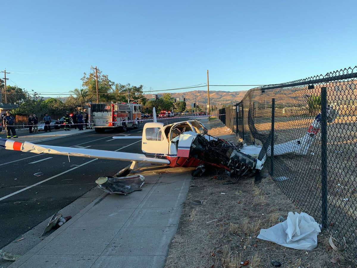 A Small Plane Crashed Into A Fence Near A Road Wallpaper