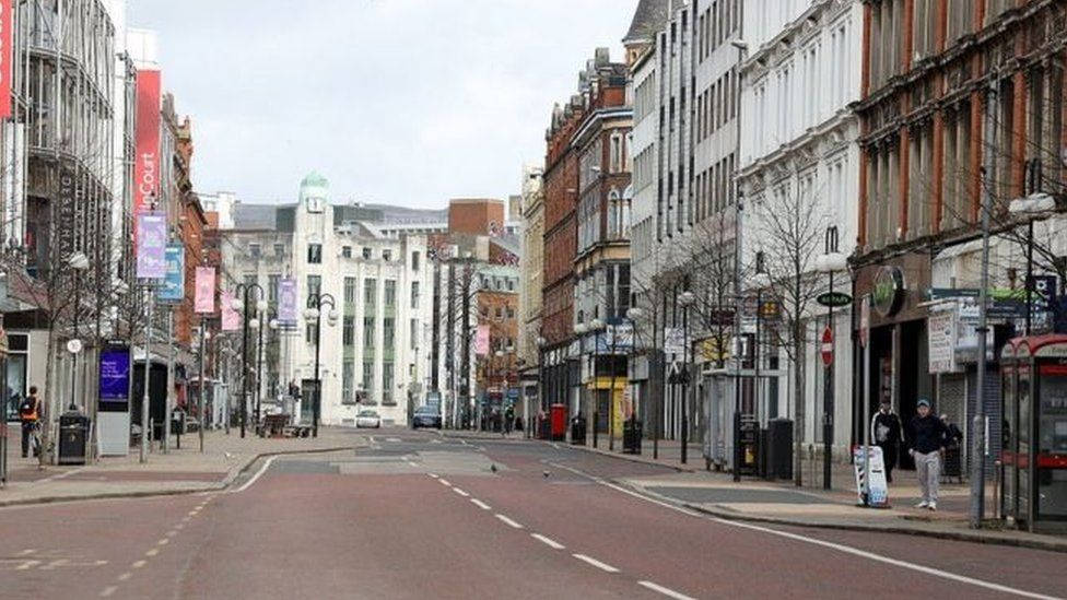 A Street With Buildings And People Walking Down It Wallpaper