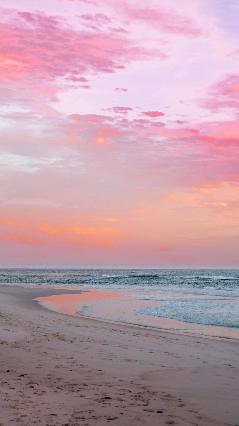 A Woman Is Walking On The Beach At Sunset Wallpaper