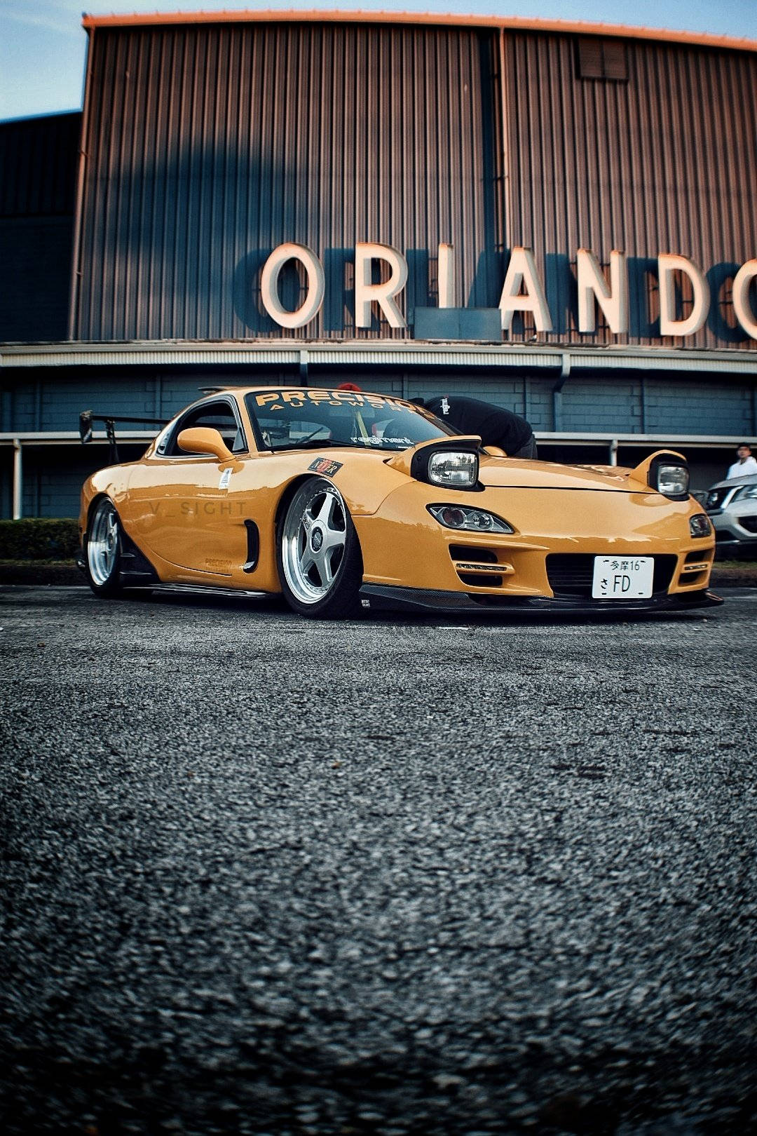 A Yellow Sports Car Parked In Front Of A Building Wallpaper