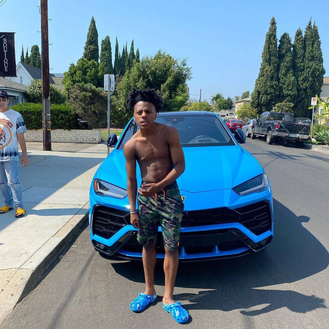 A Young Man Standing Next To A Blue Lamborghini Urus Wallpaper