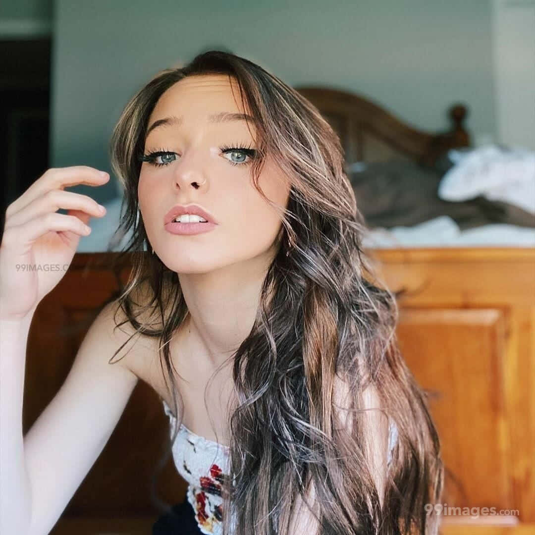 A Young Woman With Long Hair Posing On A Bed Wallpaper