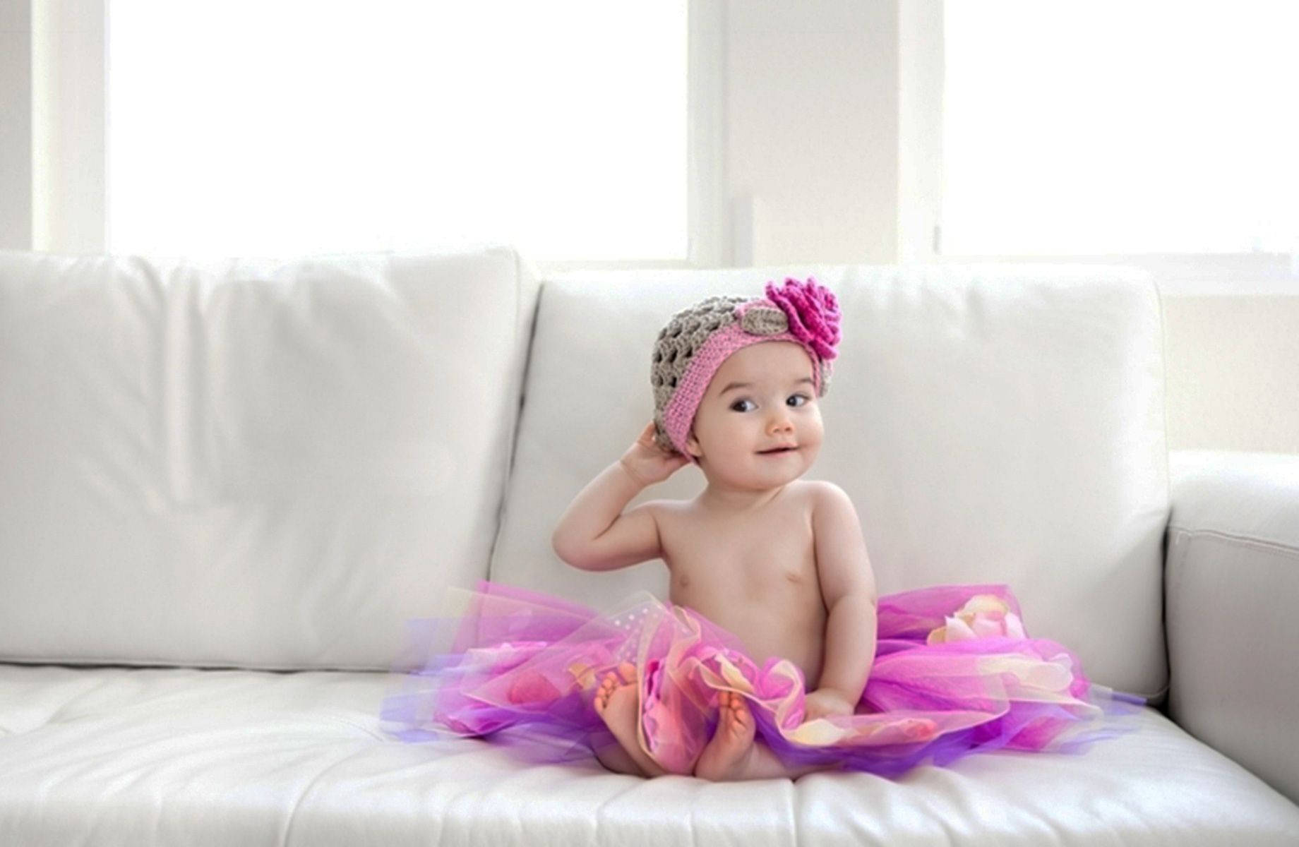 Adorable Baby Sitting On Cozy Sofa Wallpaper