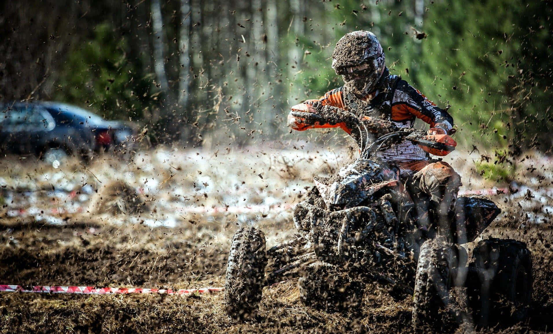 Caption: Adventure Unleashed: Superenduro Atv Diving Into A Muddy Terrain Wallpaper