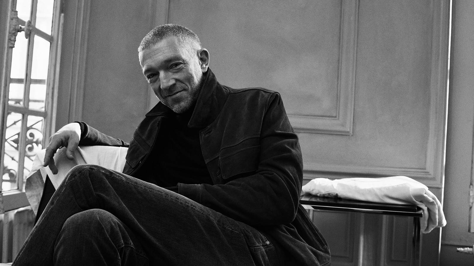 Charismatic Vincent Cassel Seated In Greyscale Photograph Wallpaper