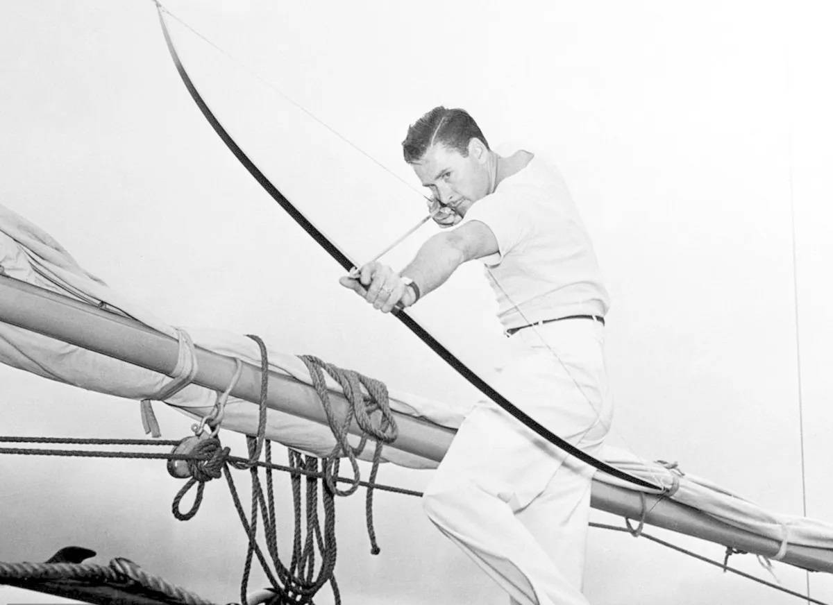 Classic Hollywood Actor, Errol Flynn, In A Dramatic Black And White Shot Aiming A Bow Wallpaper