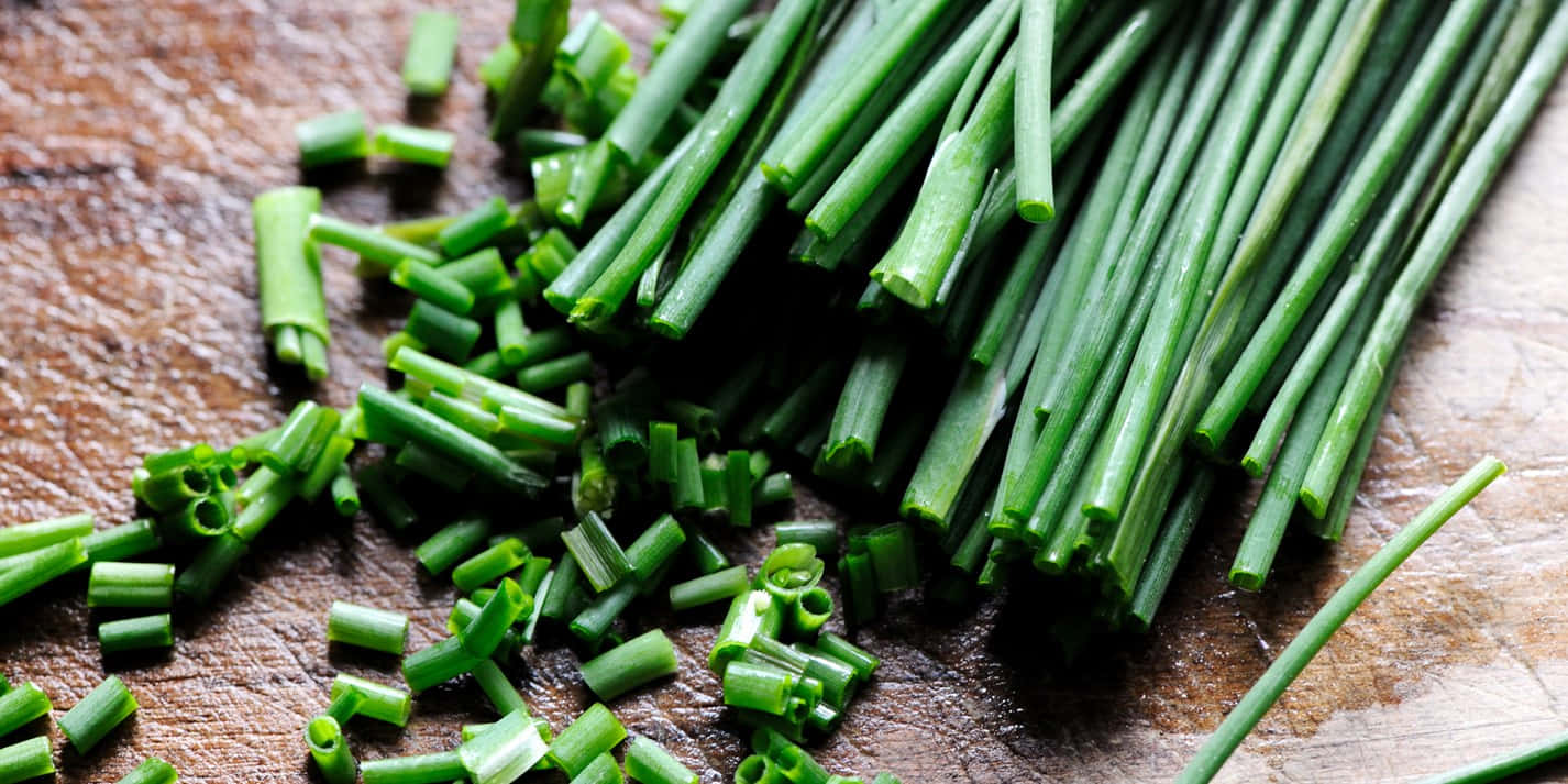 Close-up Of Fresh Green Chives On A Damp Wooden Board Wallpaper