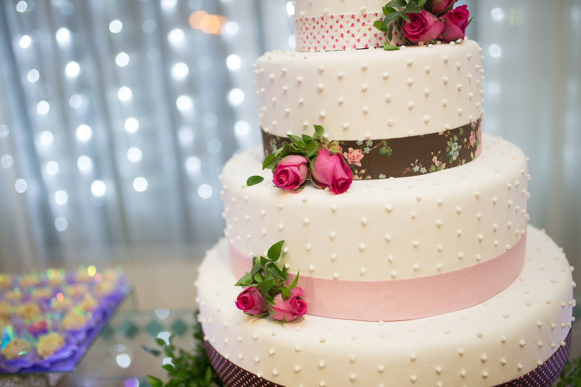 Elegant Tiered Wedding Cake Embellished With Pearls, Roses And Ribbons Wallpaper