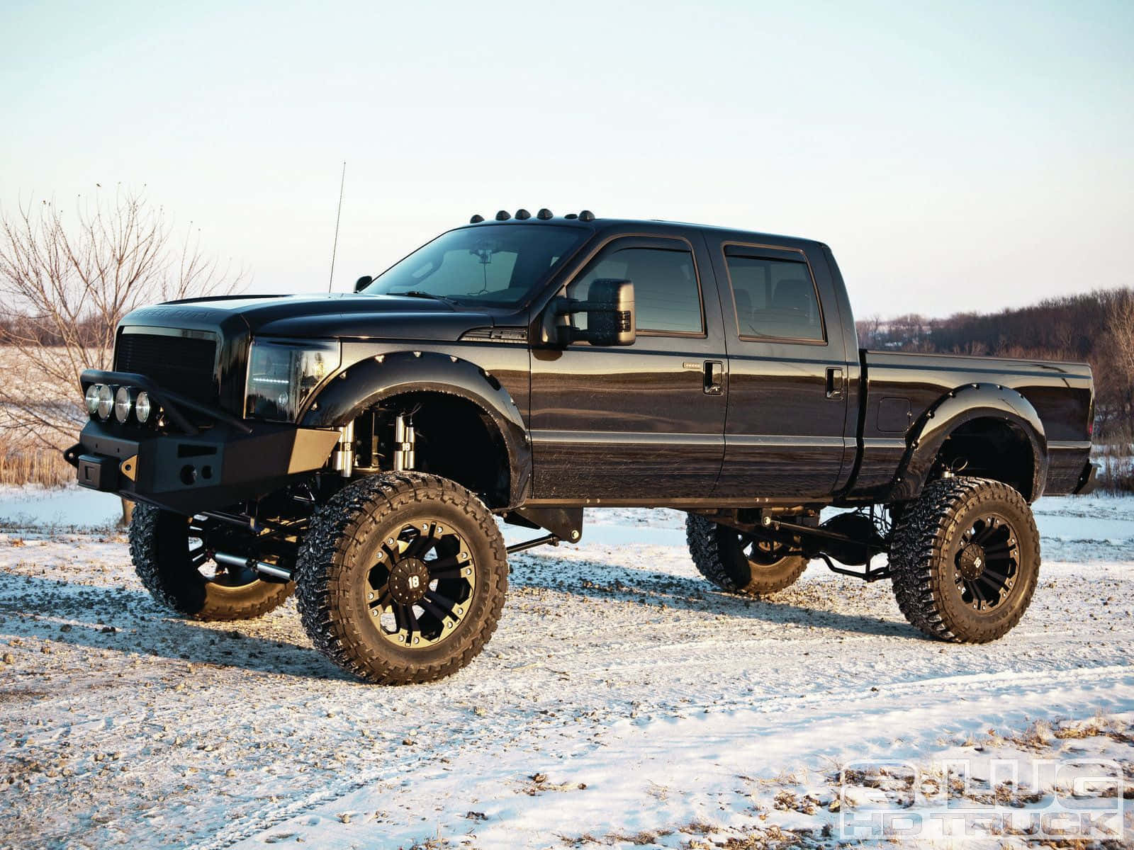 Jacked Up Trucks Driving Through Snowy Road Wallpaper