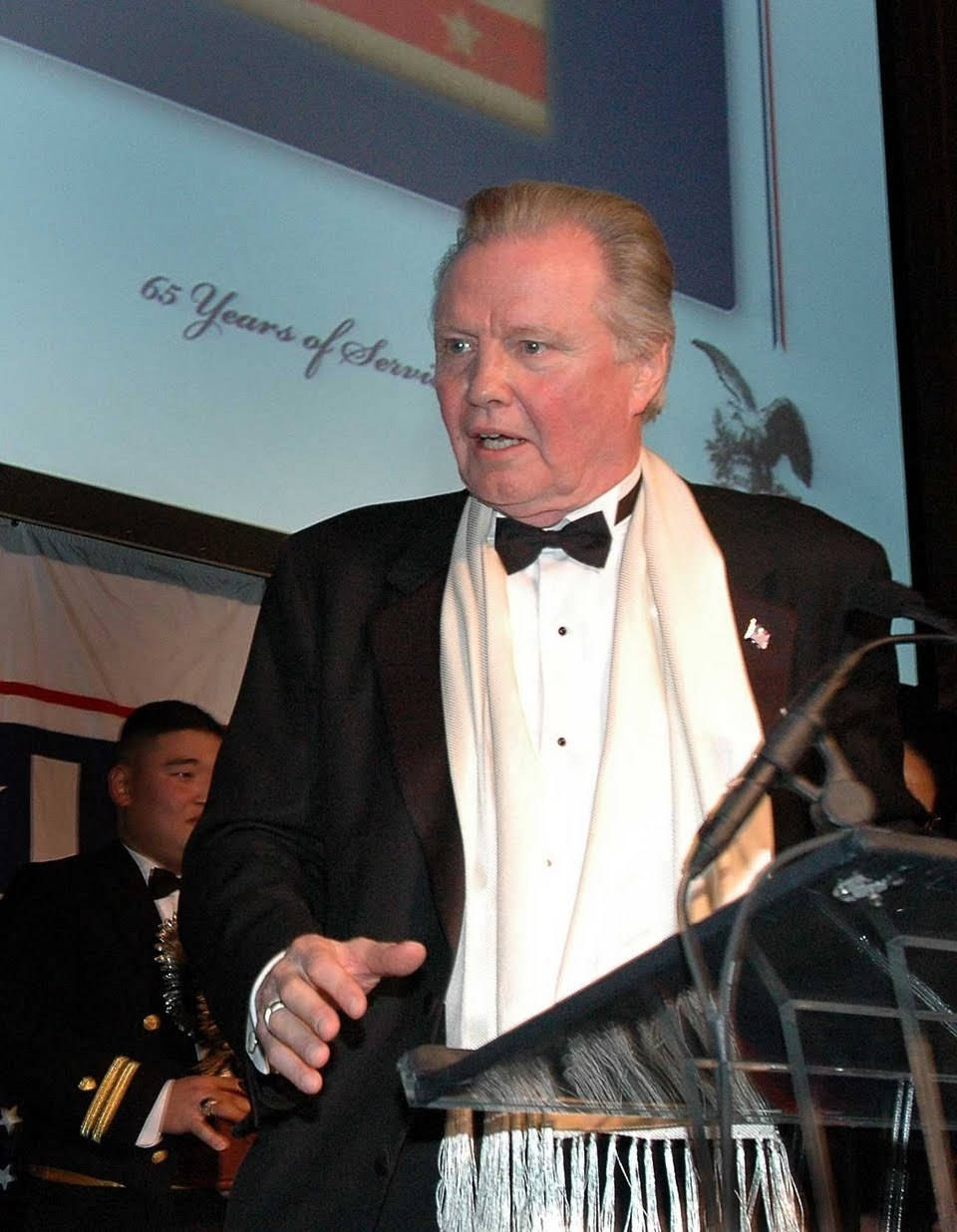 Jon Voight Delivering A Speech On A Podium Wallpaper