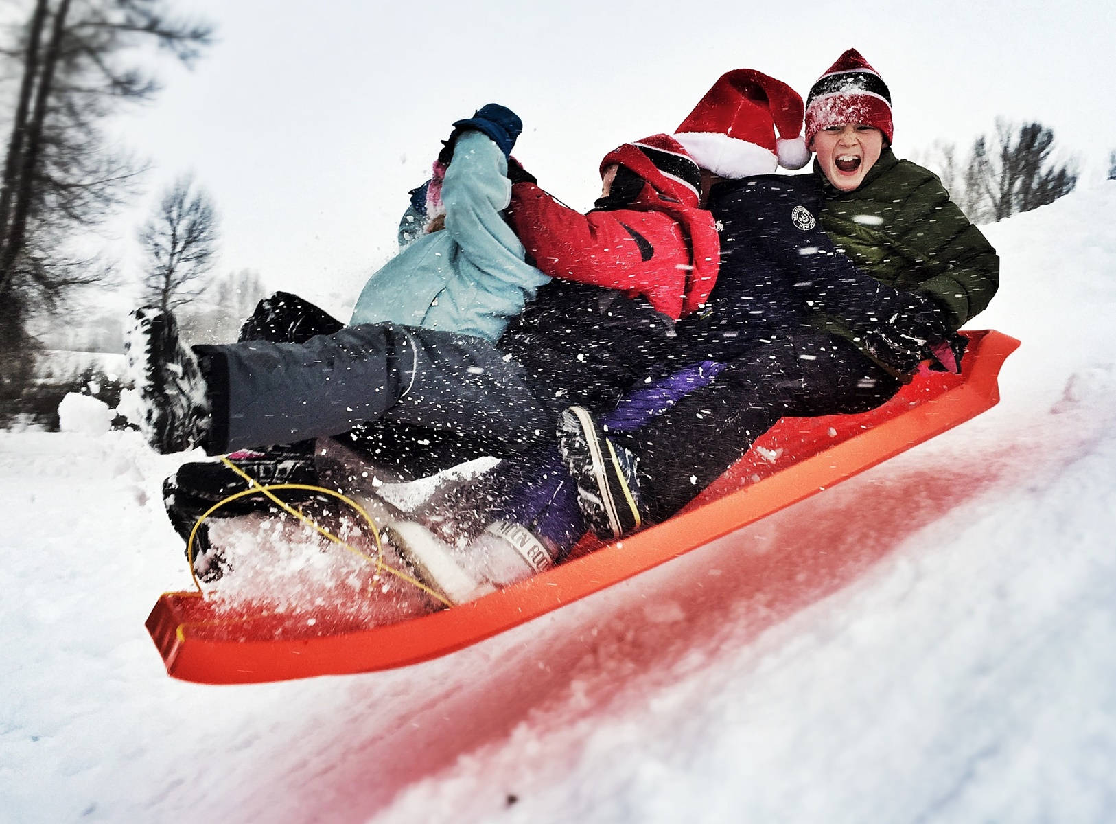 Kids Enjoy Sledding Down The Hill. Wallpaper