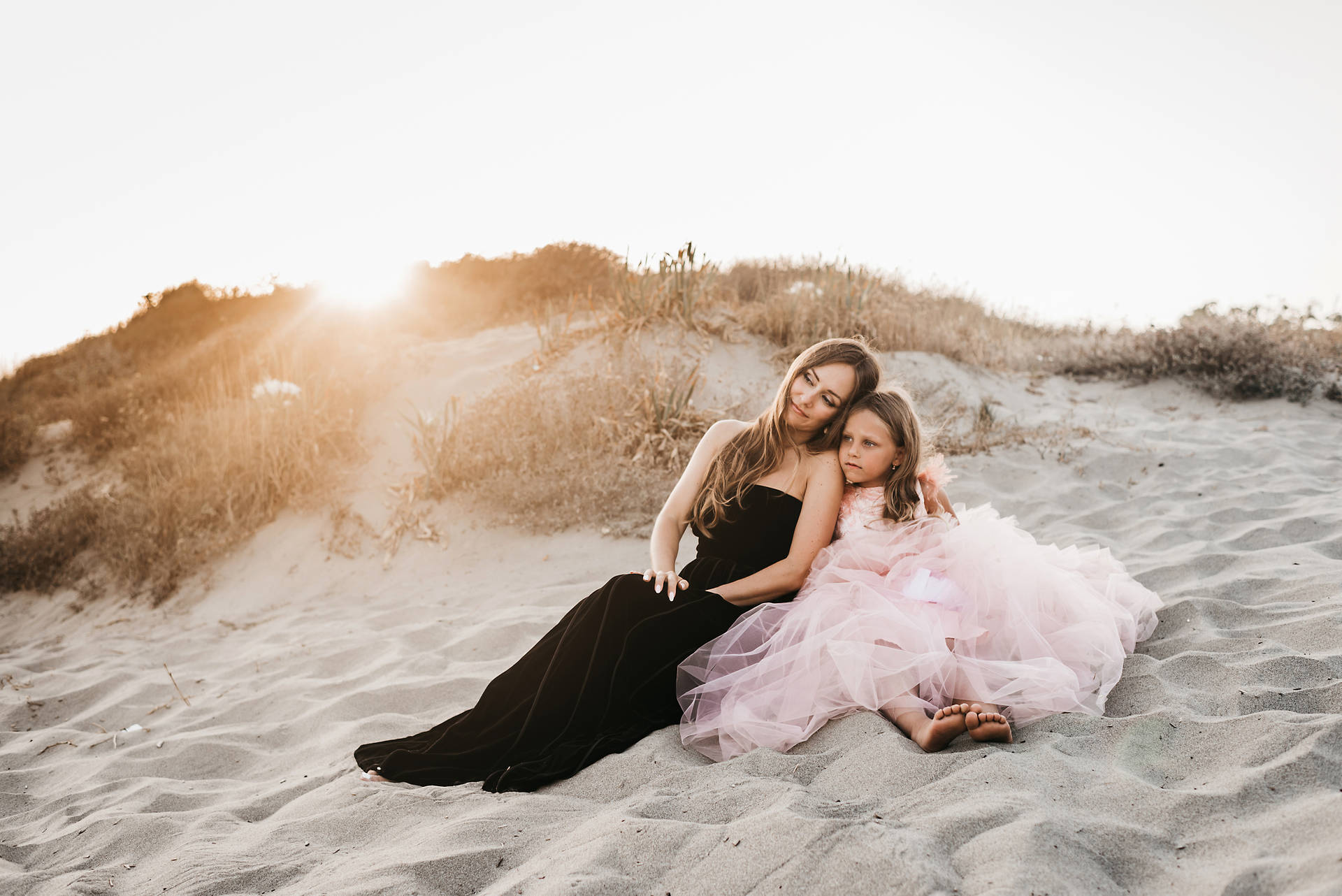 Mother And Daughter Sitting By The Beach Wallpaper