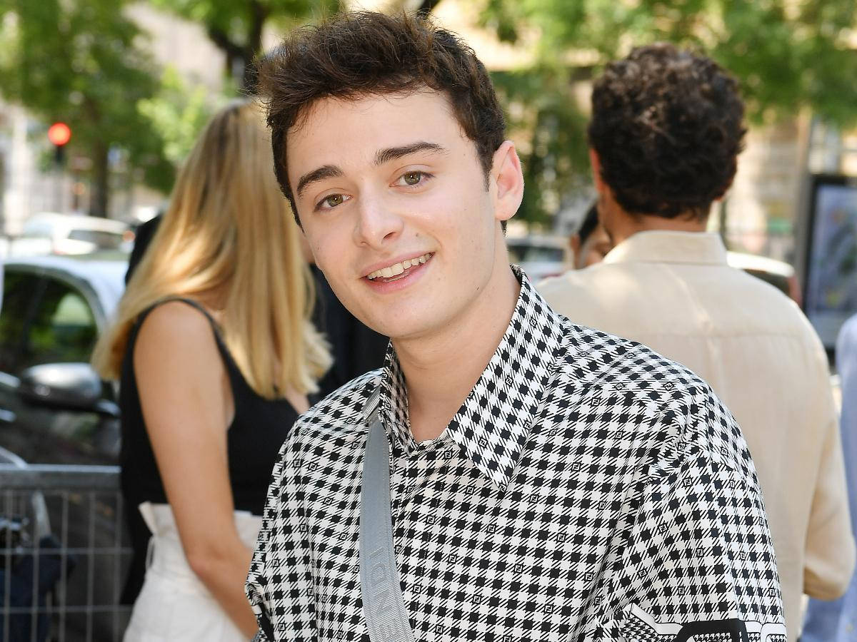 Noah Schnapp With Chekered Polo Outside Wallpaper