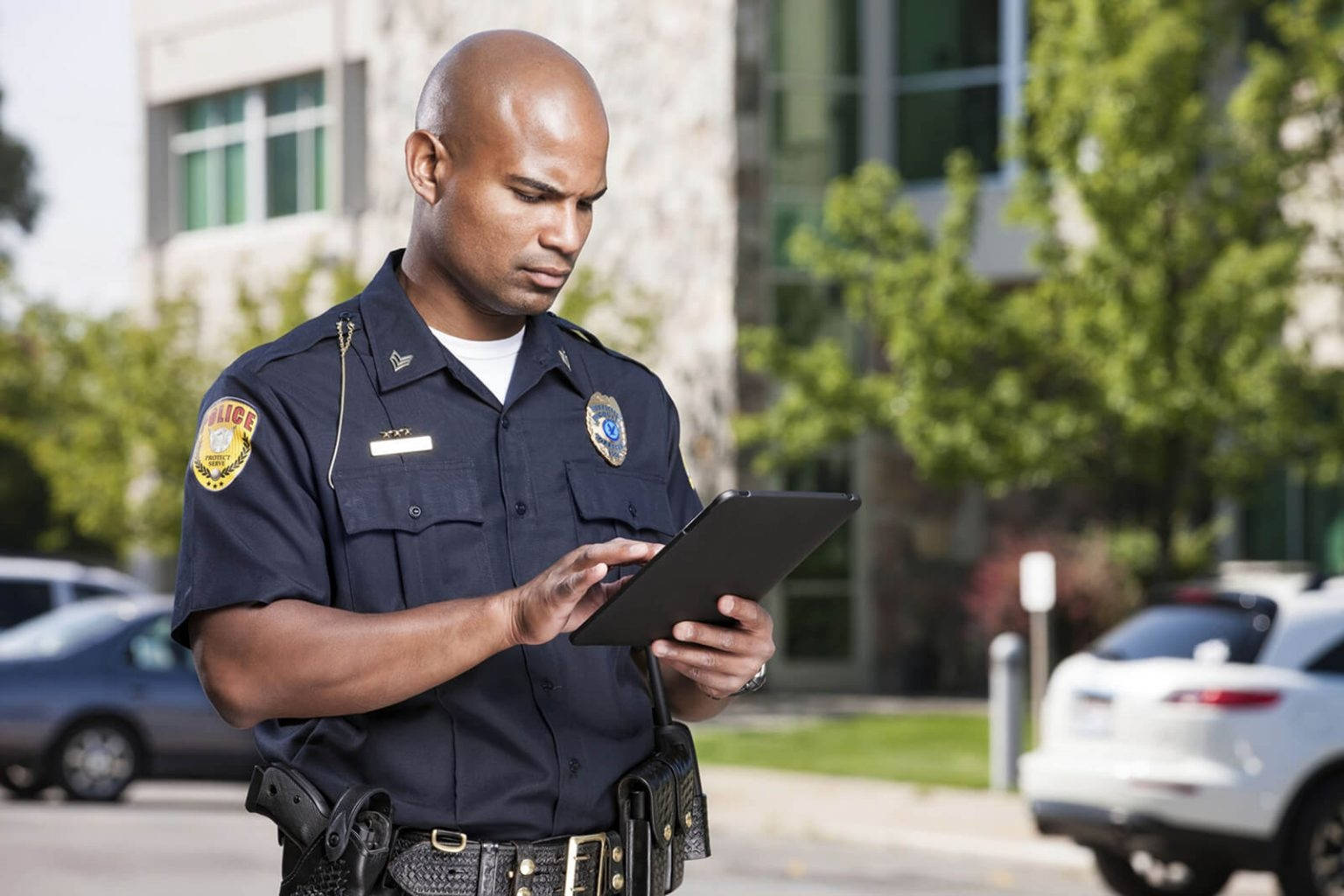 Police Officer Accessing Information On Handheld Device In The Field Wallpaper