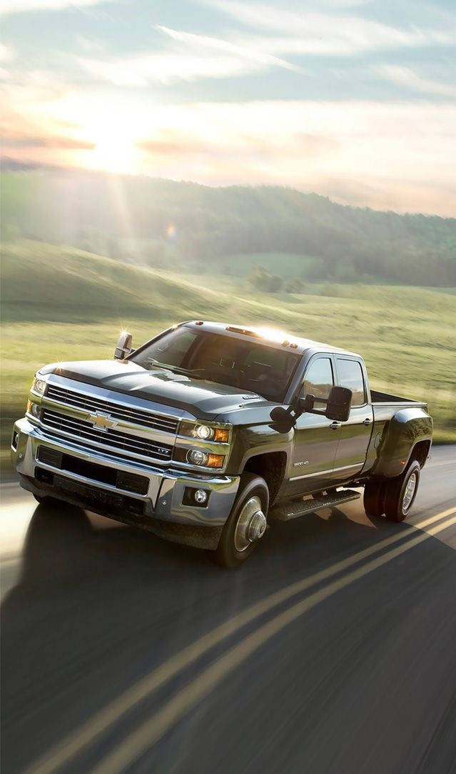 The 2016 Chevrolet Silverado Is Driving Down A Country Road Wallpaper