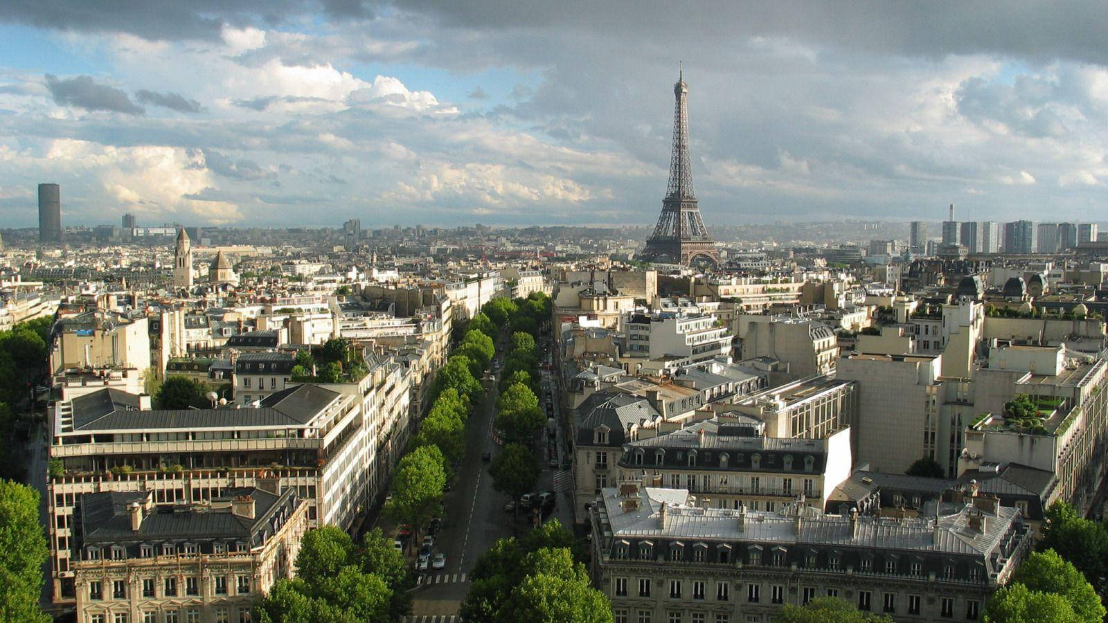 The Iconic Eiffel Tower Stands Triumphantly Against A Cloudy Paris Sky Wallpaper