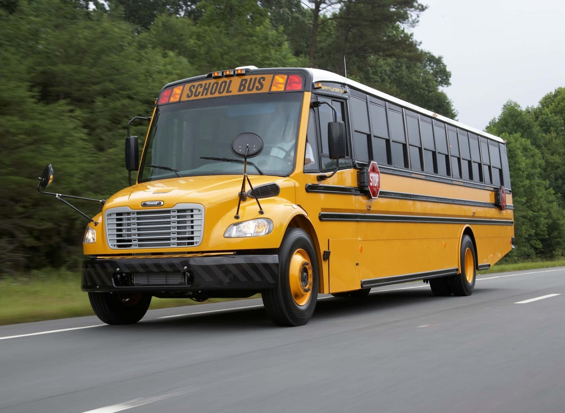 Traveling School Bus Across Road With Trees Wallpaper