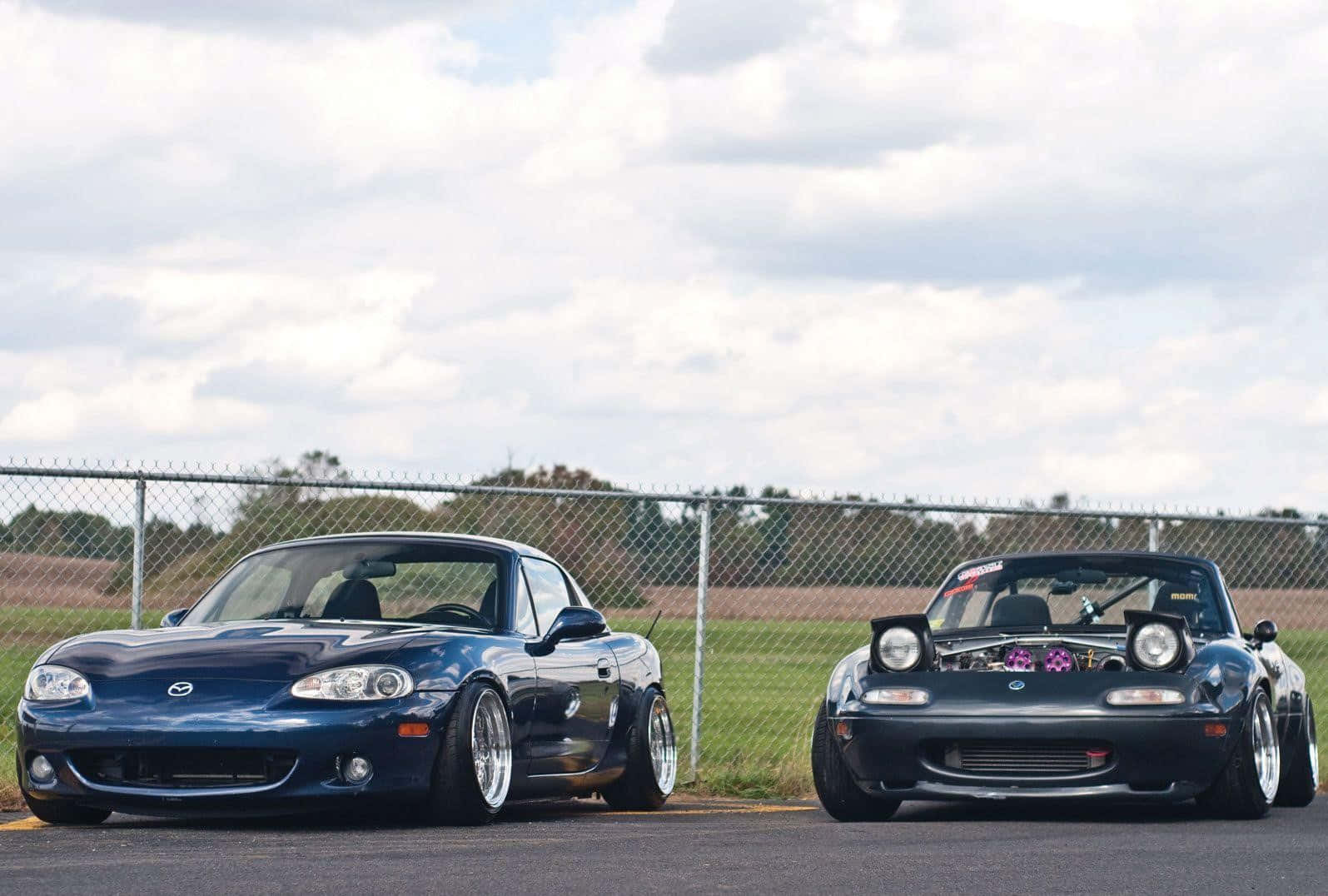 Two Cars Parked Next To Each Other On A Race Track Wallpaper