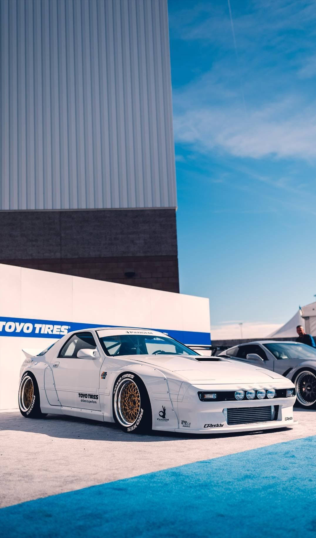 Two White Sports Cars Parked In Front Of A Building Wallpaper