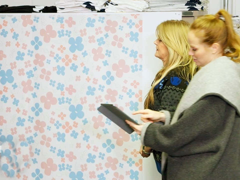 Two Women Looking At A Wall Of Shirts Wallpaper