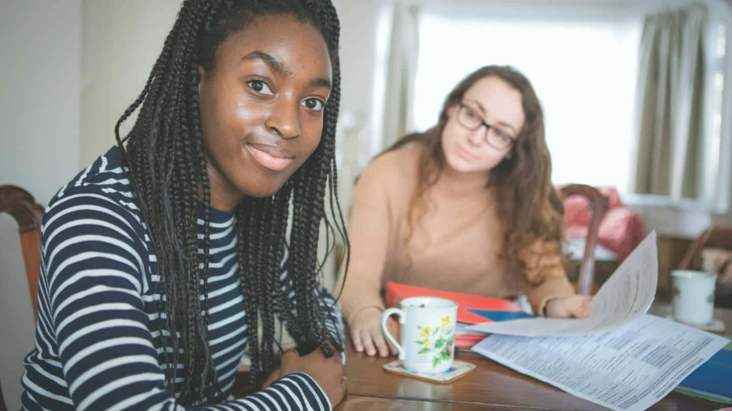 Two Young Women Sitting Together Wallpaper