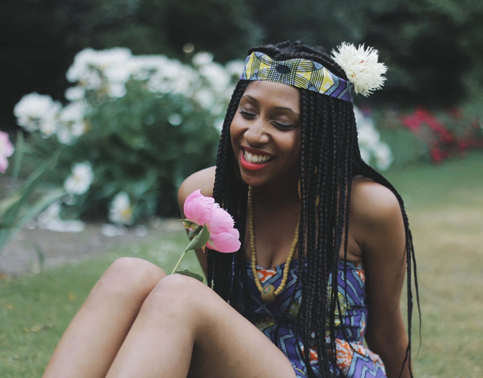 Young Black Woman Smelling A Flower Wallpaper