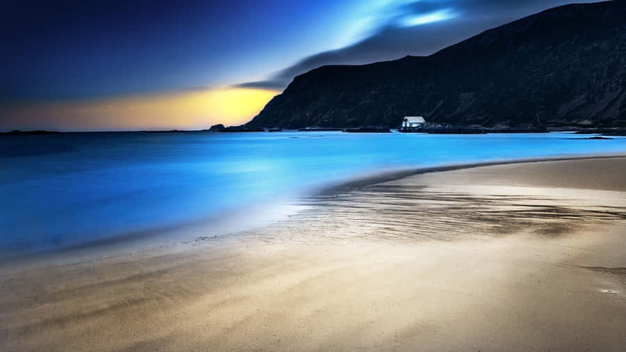 A Beach With A Lighthouse And A Blue Sky Wallpaper