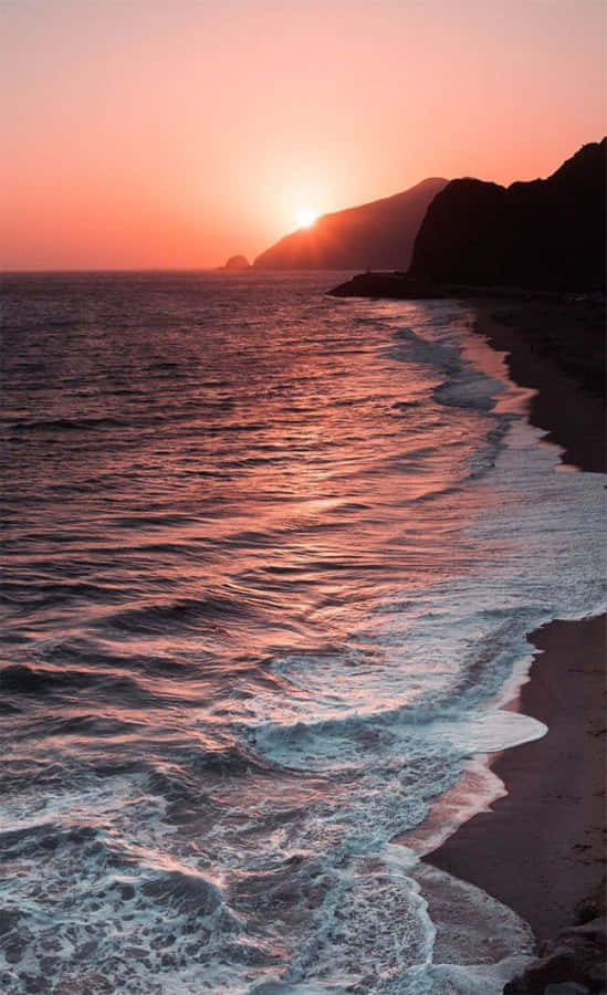 A Beach With Waves And A Sunset Wallpaper