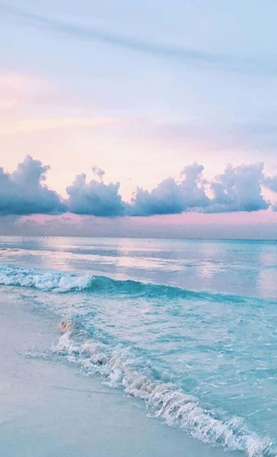 A Beach With Waves And Clouds At Sunset Wallpaper