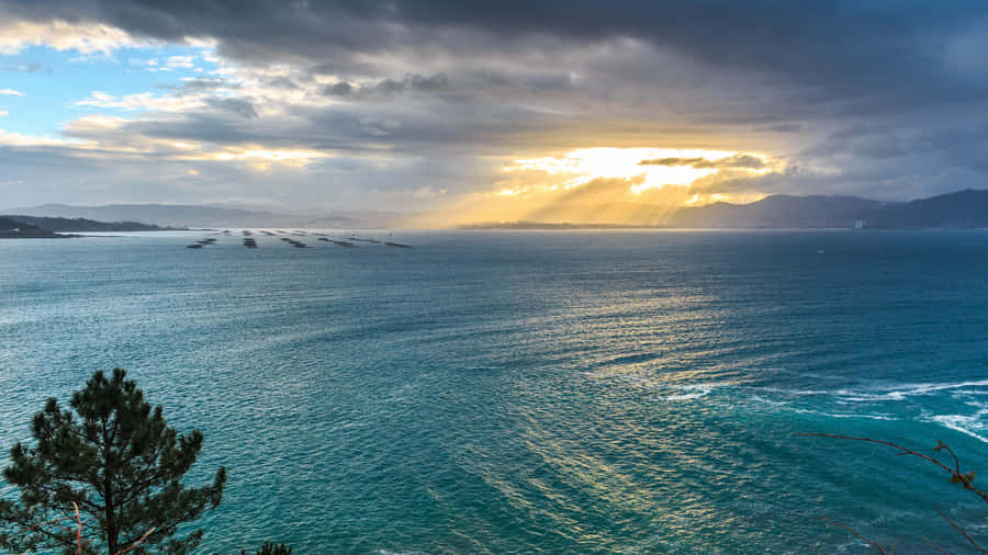 A Beautiful Sunset Over The Ocean With Clouds In The Sky Wallpaper