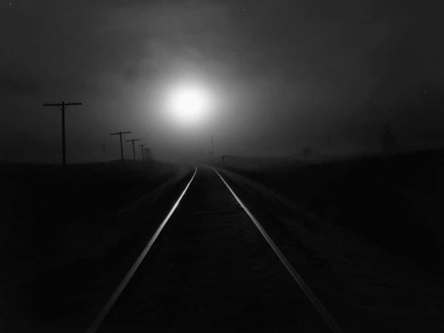 A Black And White Photo Of A Train Track In The Fog Wallpaper