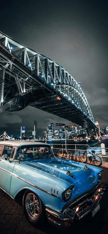 A Blue Car Parked In Front Of A Bridge Wallpaper