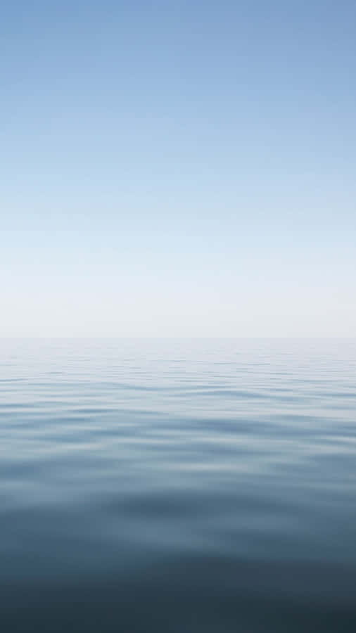 A Blue Ocean With A White Sky Wallpaper
