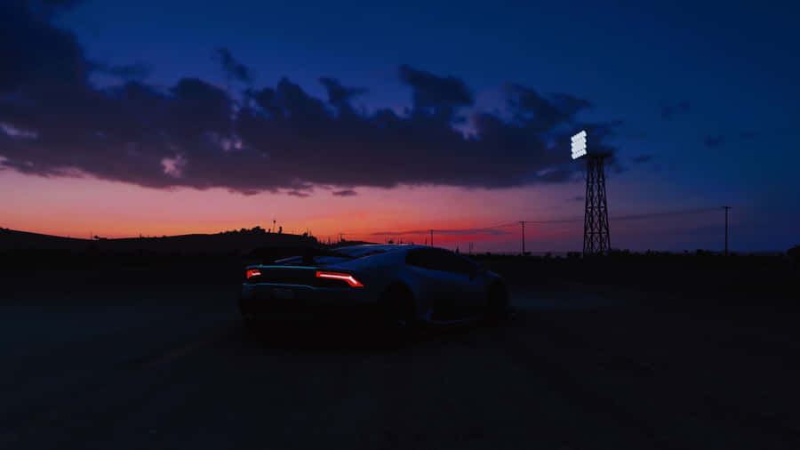 A Car Is Parked In The Middle Of A Road At Sunset Wallpaper