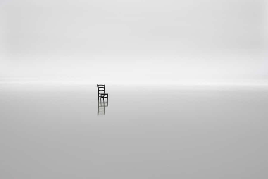 A Chair Sits On A Solitary Island In The Middle Of The Ocean Wallpaper