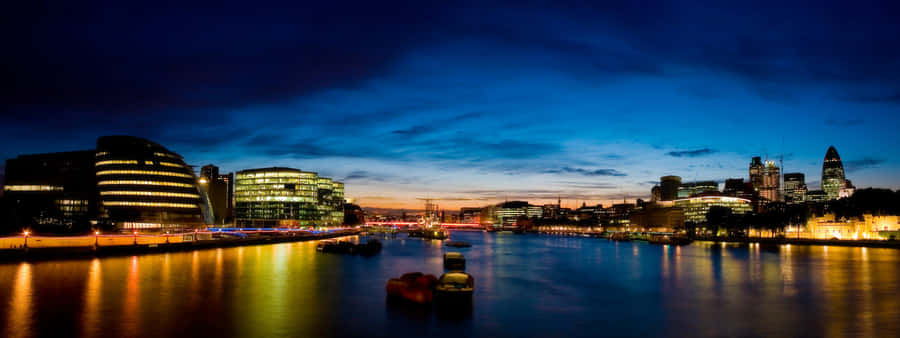 A City At Night With A River And Buildings Wallpaper