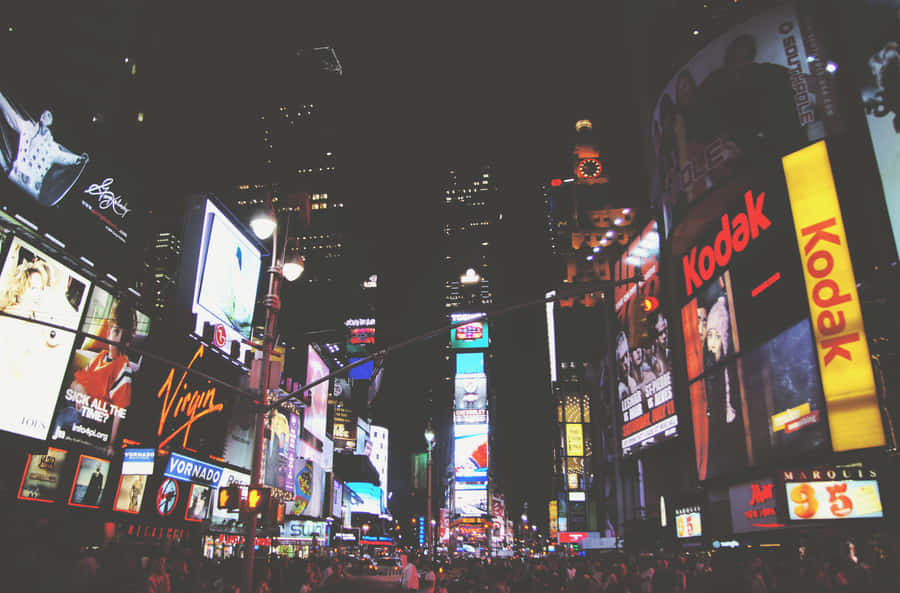 A City At Night With Many People Walking Around Wallpaper