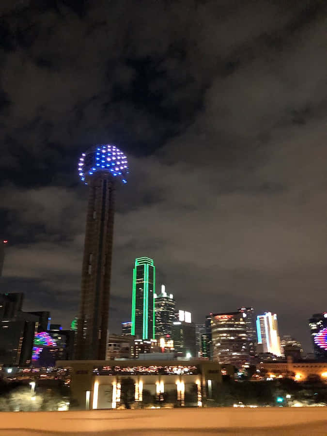 A City With A Blue And Green Light Tower Wallpaper