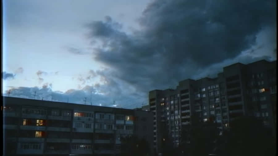 A Dark Sky Over A City With Buildings Wallpaper